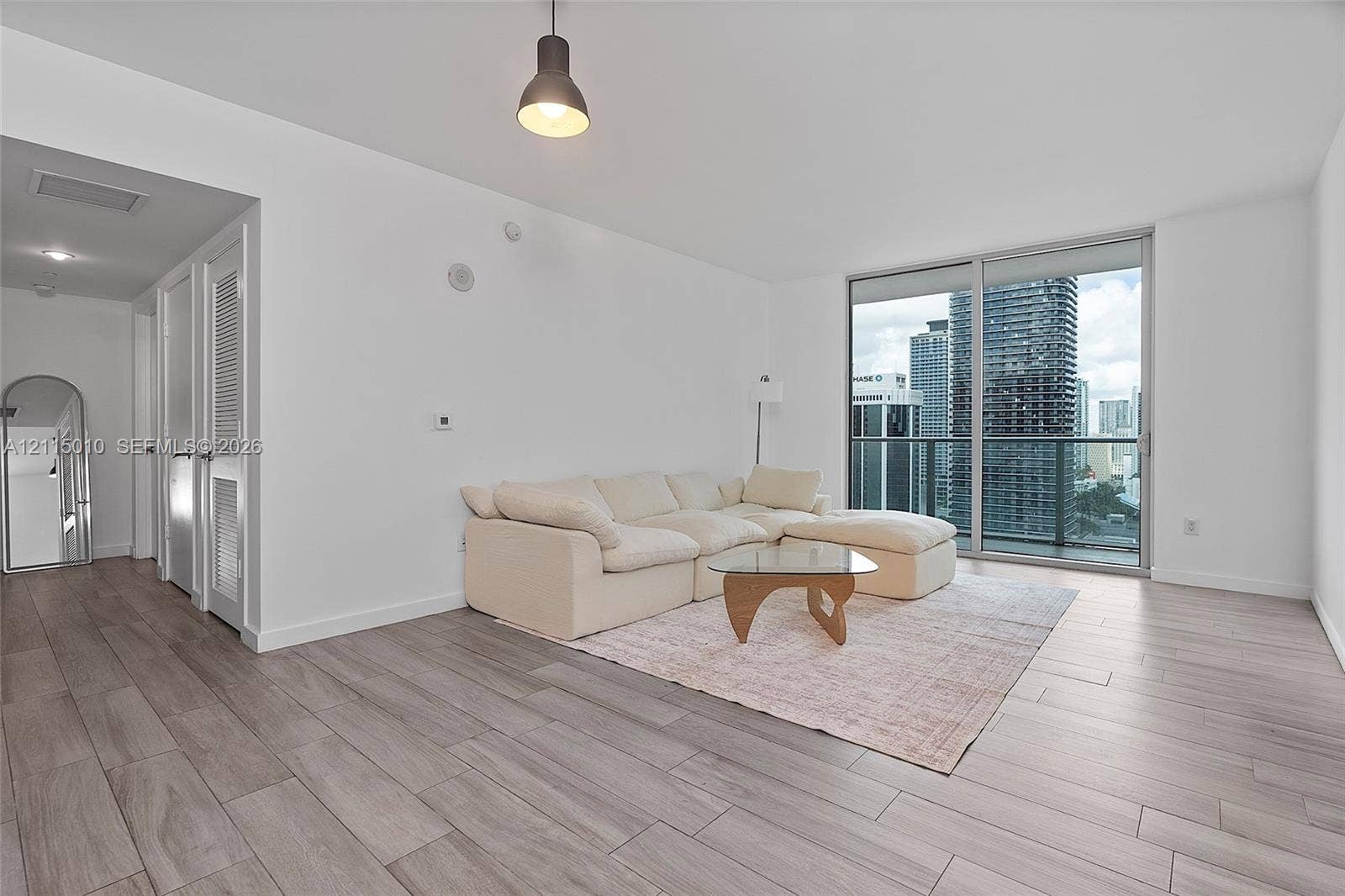 1100 S Miami Avenue, #2407, Miami, FL 33130 Wood-finish flooring, floor-to-ceiling glass sliding doors, private balcony with metal railing, and pendant lighting
