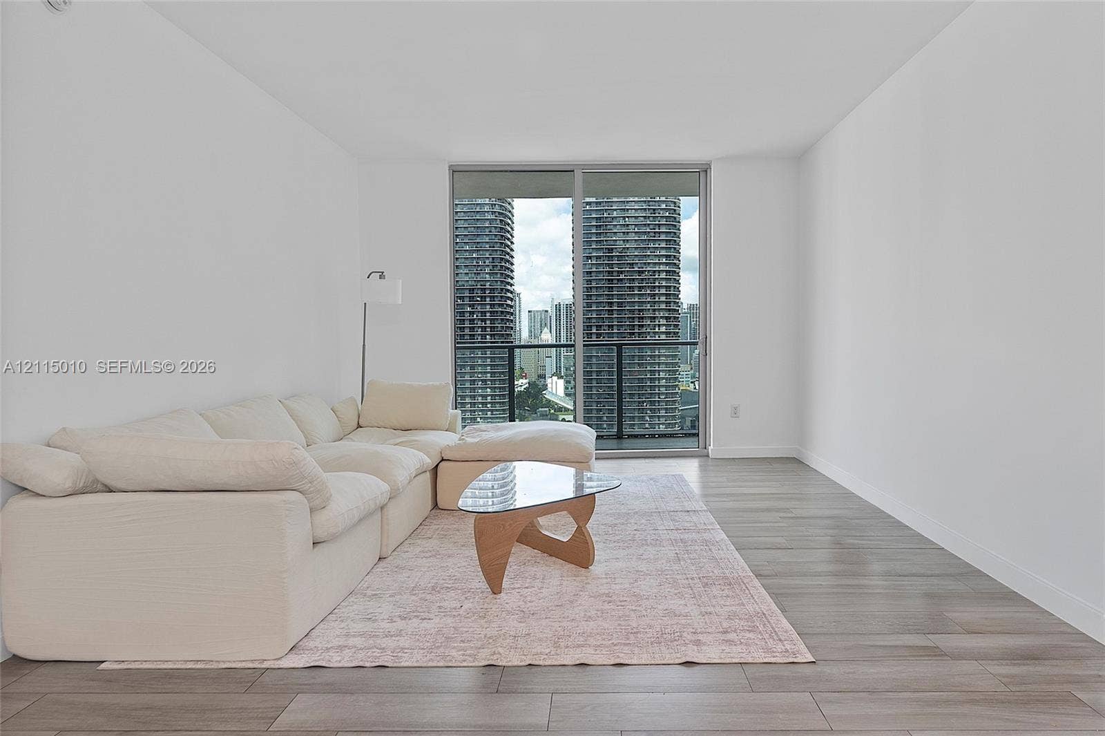 1100 S Miami Avenue, #2407, Miami, FL 33130 Open-concept room featuring wood-finish flooring, floor-to-ceiling glass sliding doors, and a glass-railing balcony