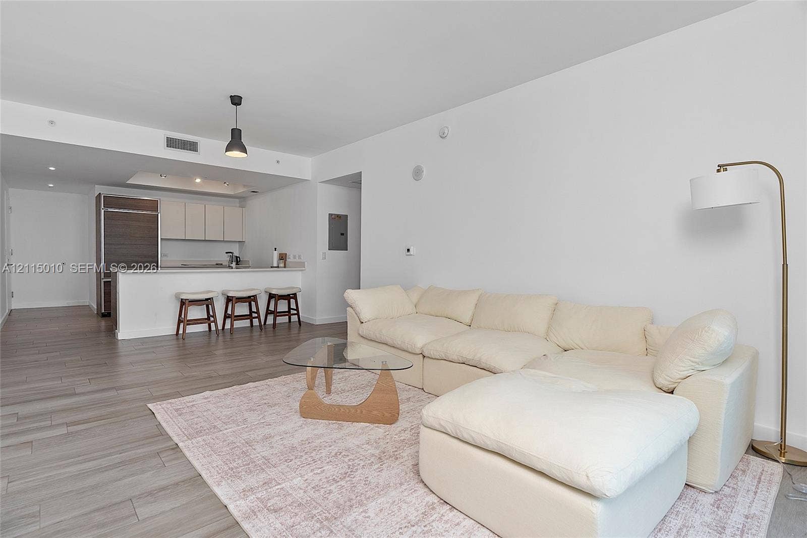 1100 S Miami Avenue, #2407, Miami, FL 33130 Open-concept interior featuring wood-finish flooring, a kitchen island with stone countertop, two-toned cabinetry, and minimalist pendant lighting