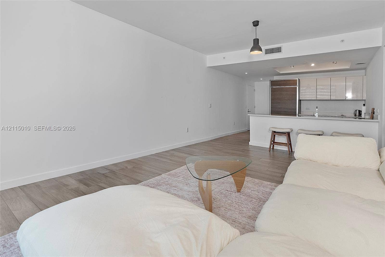 1100 S Miami Avenue, #2407, Miami, FL 33130 Open-concept living space featuring wood-finish flooring, kitchen with high-gloss cabinetry, integrated refrigerator, and a breakfast bar