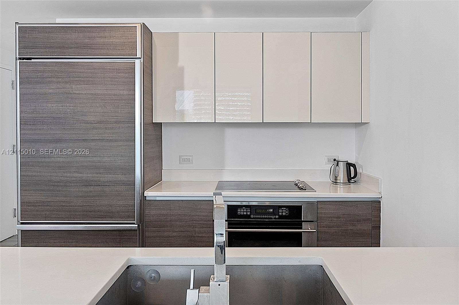 1100 S Miami Avenue, #2407, Miami, FL 33130 Kitchen featuring high-gloss cabinetry, wood-finish paneling, an integrated refrigerator, a built-in oven with a cooktop, and an undermount sink with a chrome faucet