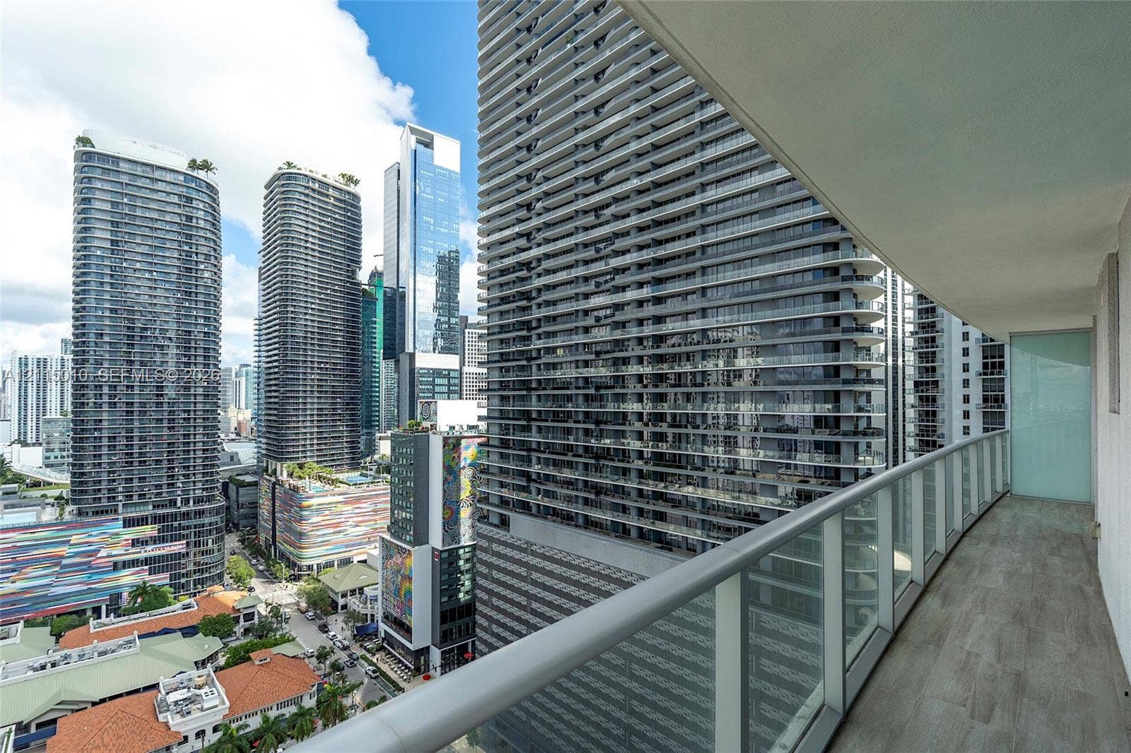 1100 S Miami Avenue, #2407, Miami, FL 33130 Covered balcony featuring wood-finish flooring, glass panel railing, and high-rise urban surroundings