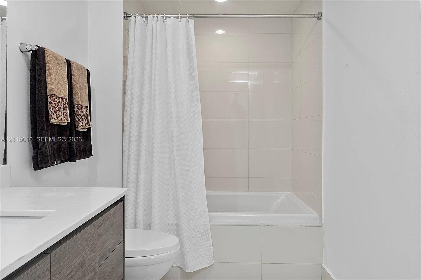 1100 S Miami Avenue, #2407, Miami, FL 33130 Bathroom featuring a floating vanity with stone countertop, recessed lighting, and a tub with large-format wall tile surround