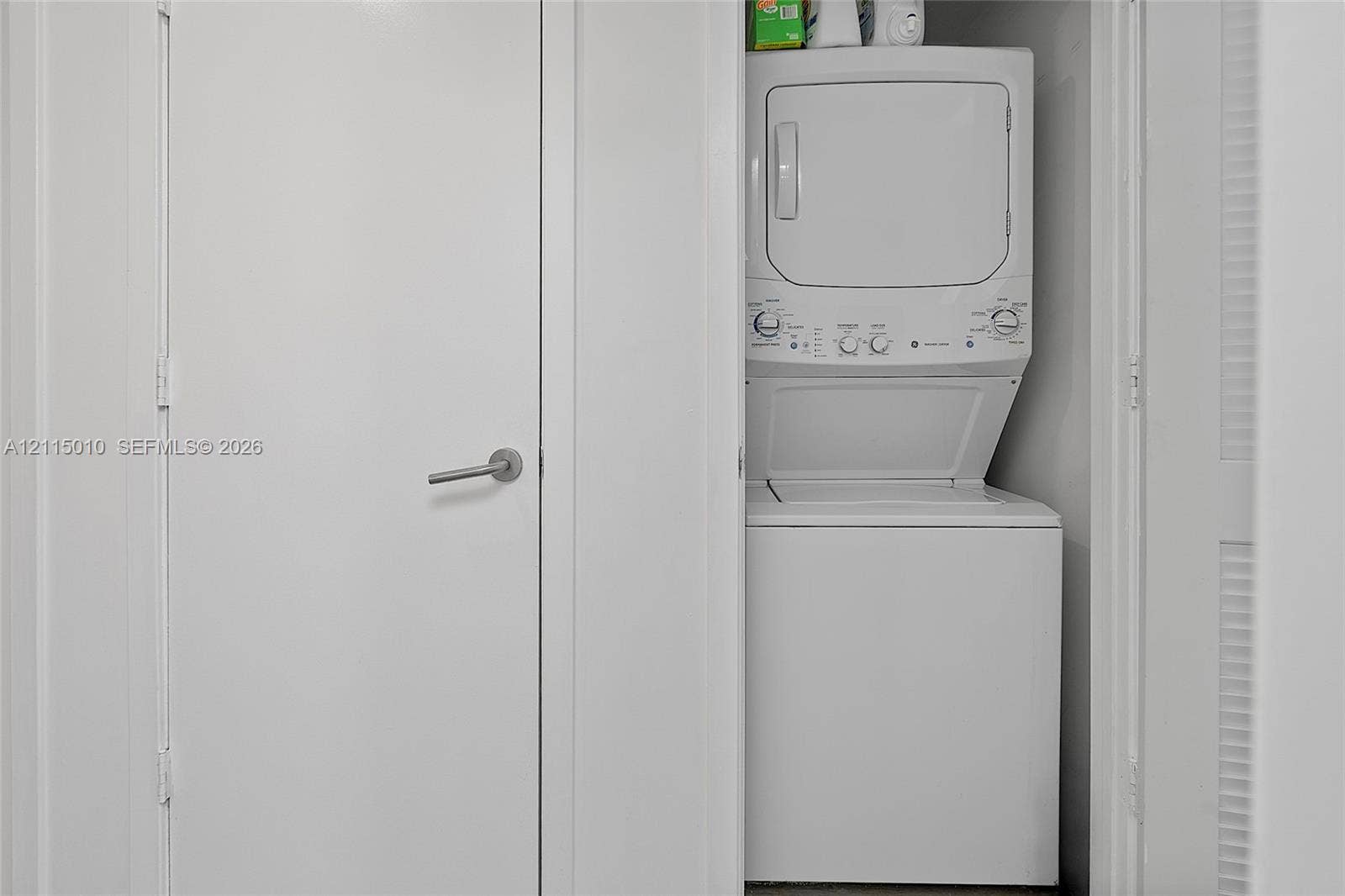 1100 S Miami Avenue, #2407, Miami, FL 33130 Stacked white laundry unit enclosed in a dedicated closet space with a solid-core door and metal lever handle