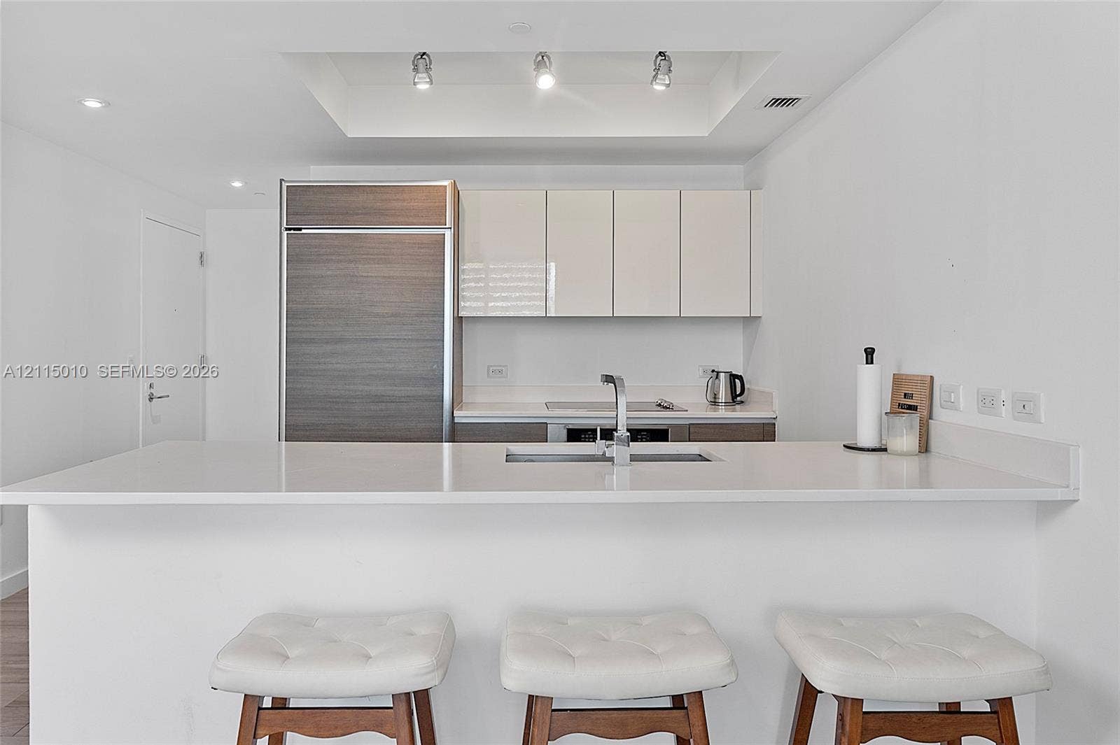 1100 S Miami Avenue, #2407, Miami, FL 33130 Kitchen featuring a solid-surface countertop, integrated refrigerator, flat-panel cabinetry, recessed tray ceiling lighting, and a dual-basin undermount sink