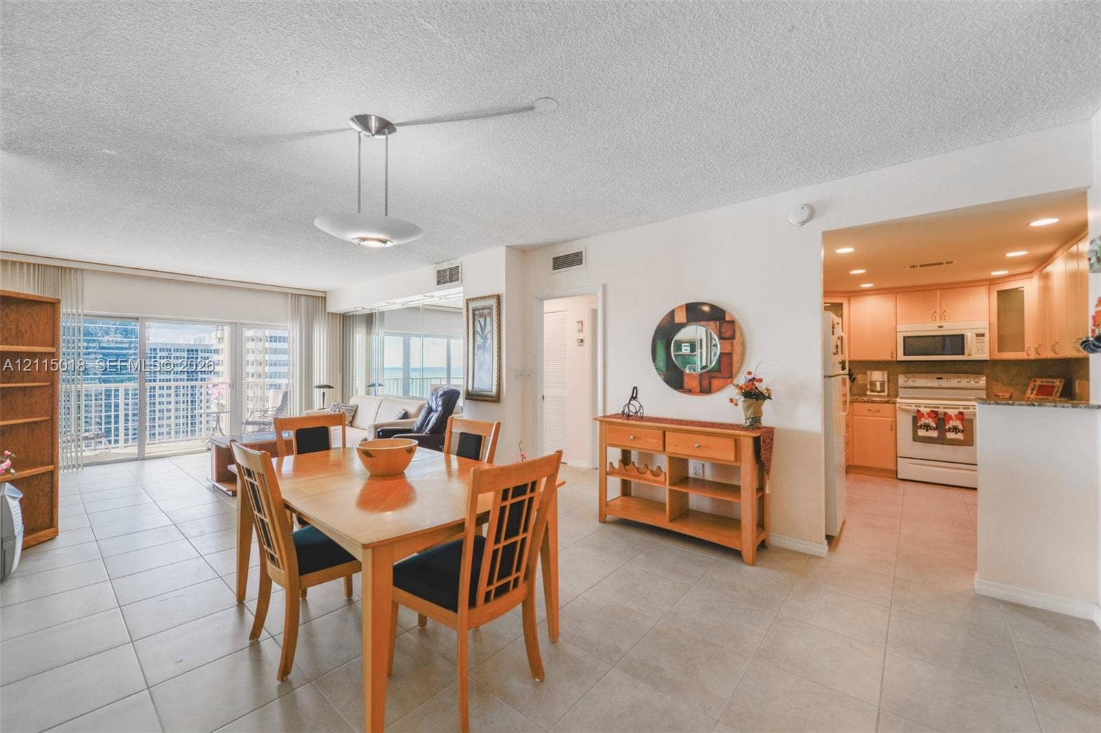 1950 S Ocean Drive, #20N, Hallandale Beach, FL 33009 Open-concept area featuring light-toned tile flooring, recessed kitchen lighting, a modern multi-light pendant fixture, and a glass sliding door providing outdoor access