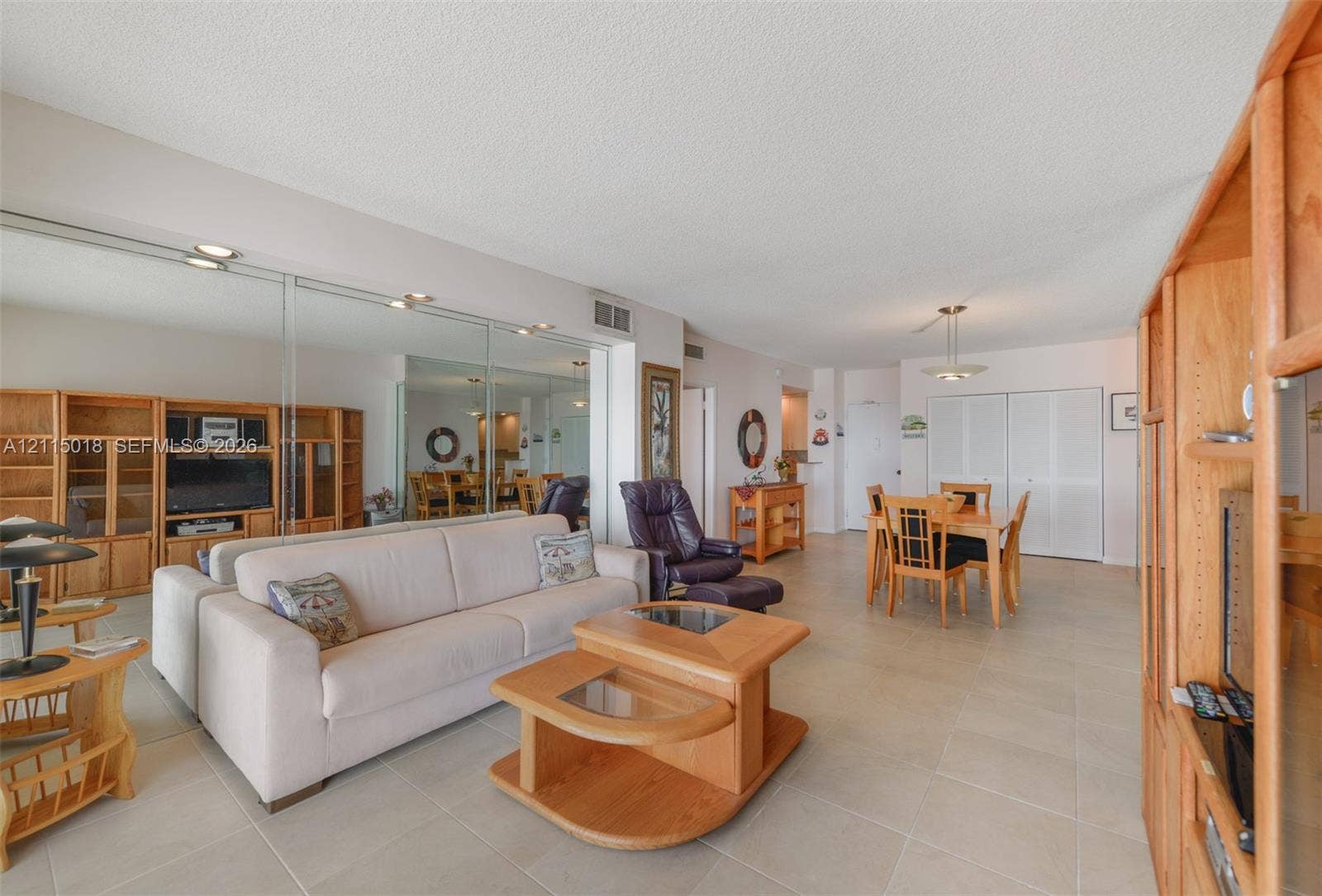 1950 S Ocean Drive, #20N, Hallandale Beach, FL 33009 Open-concept interior featuring large-format ceramic tile flooring, mirrored wall panels, and built-in wood cabinetry