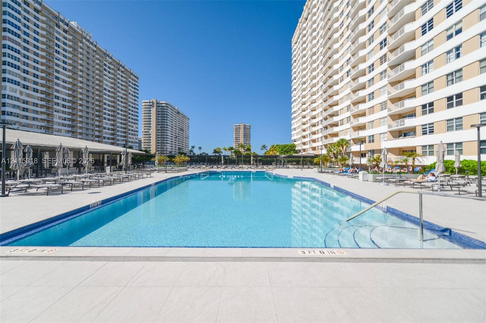 1950 S Ocean Drive, #20N, Hallandale Beach, FL 33009 Rectangular swimming pool featuring tile coping, stepped entry, and expansive paved surround