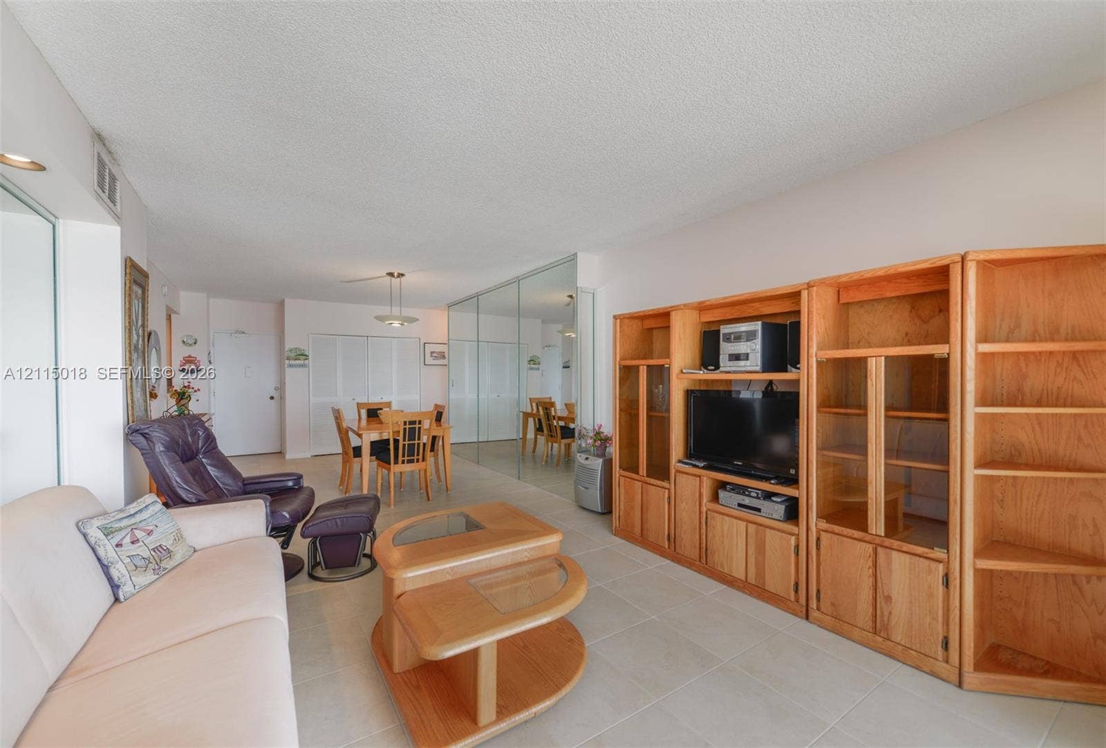 1950 S Ocean Drive, #20N, Hallandale Beach, FL 33009 Large built-in light-tone wood shelving unit with glass-paneled cabinetry, mirrored wall panels, and tile flooring