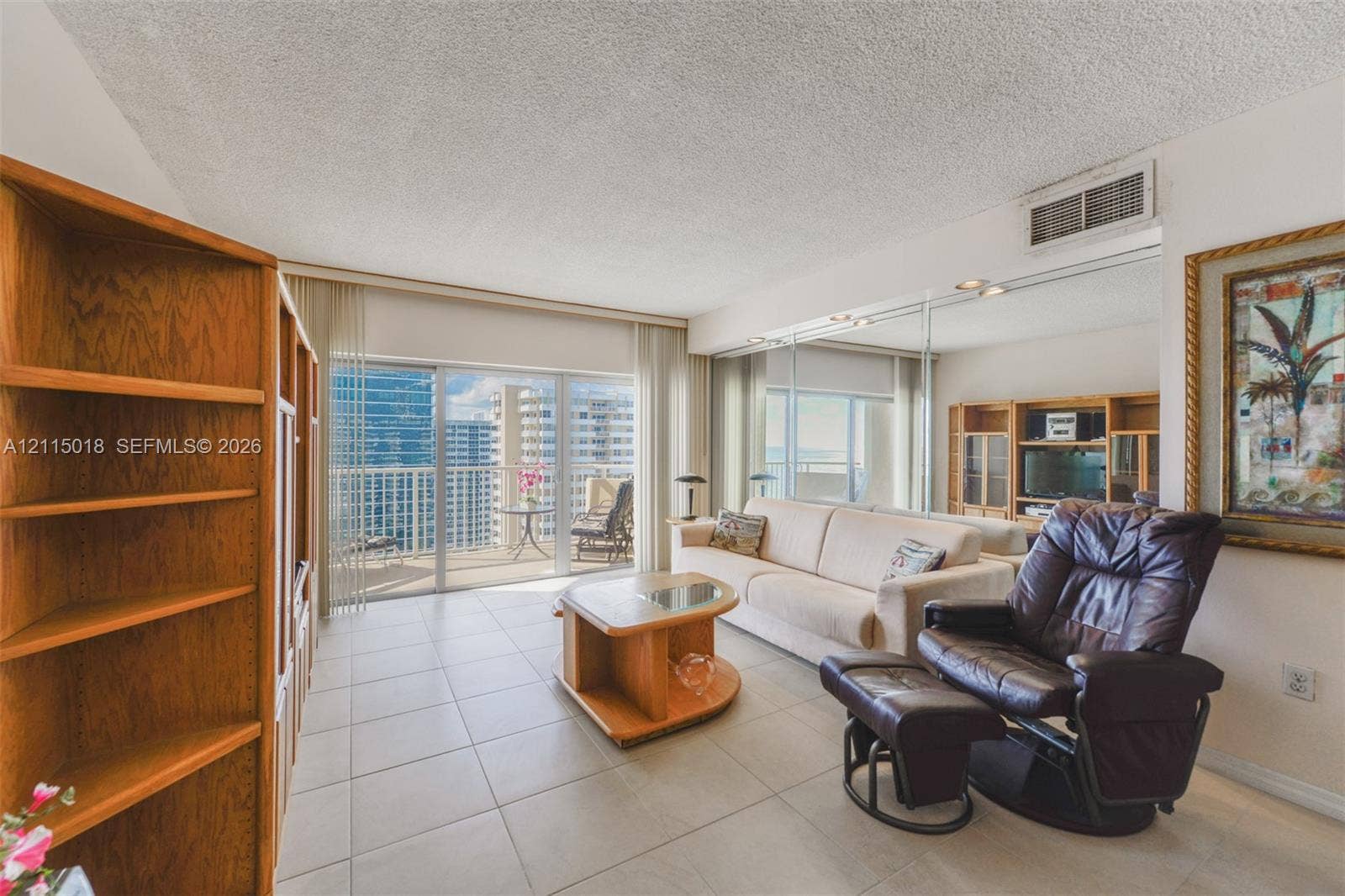 1950 S Ocean Drive, #20N, Hallandale Beach, FL 33009 Large-format tile flooring, mirrored wall accents, built-in wooden shelving, and floor-to-ceiling glass doors opening to a balcony