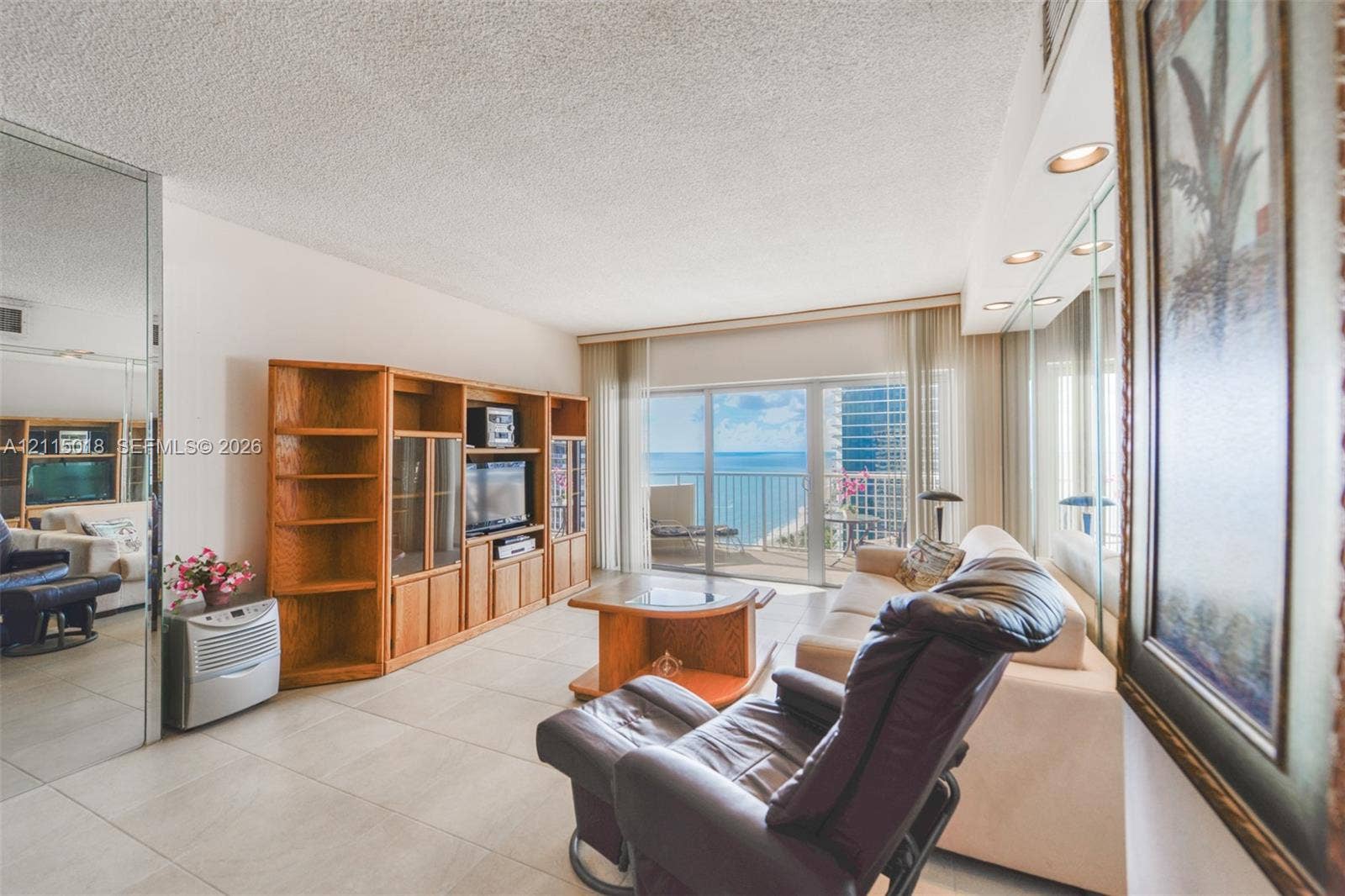1950 S Ocean Drive, #20N, Hallandale Beach, FL 33009 Large-format tile flooring, built-in wooden cabinetry, recessed ceiling lighting, wall-to-wall mirrored paneling, and sliding glass doors opening to a balcony