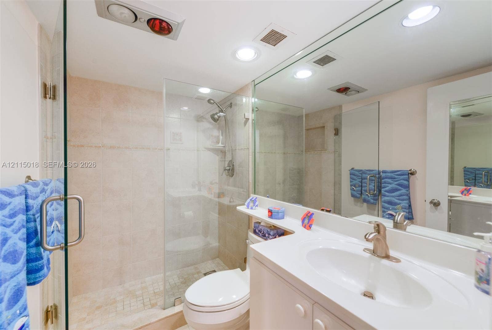 1950 S Ocean Drive, #20N, Hallandale Beach, FL 33009 Full-width mirror over a white vanity with an integrated basin, glass-enclosed shower featuring stone-finish wall tile, and recessed lighting