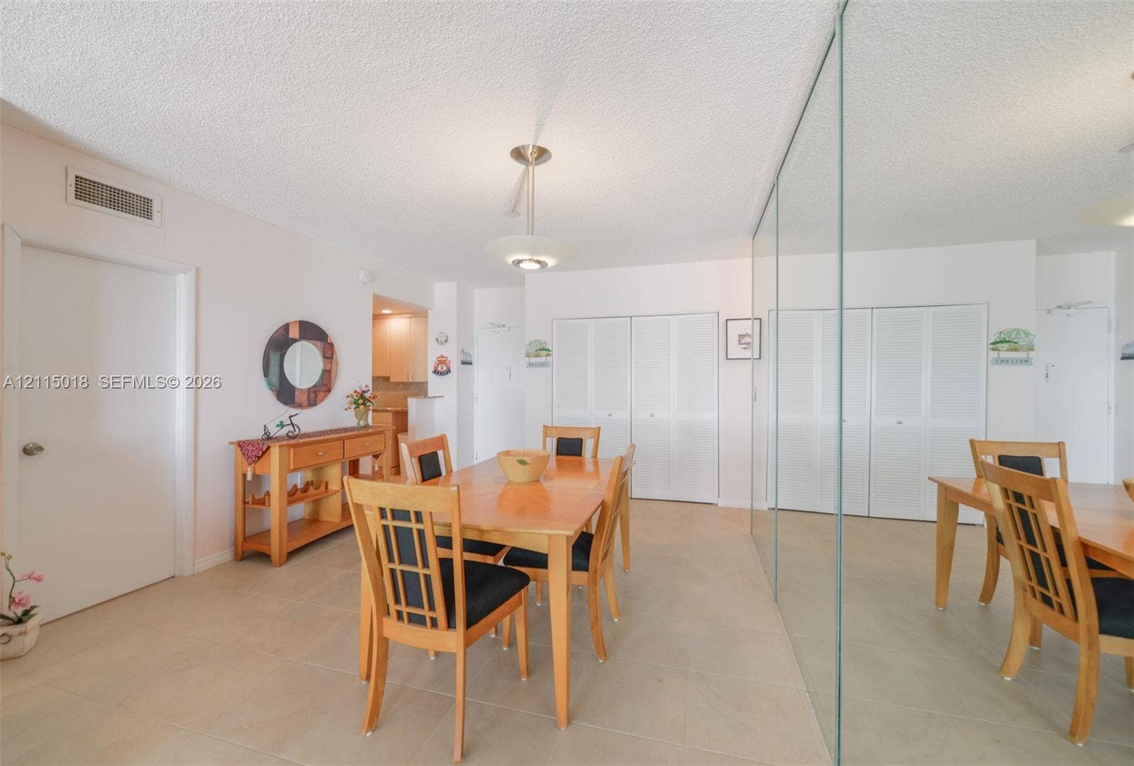 1950 S Ocean Drive, #20N, Hallandale Beach, FL 33009 Large-format neutral floor tiling, floor-to-ceiling mirrored wall paneling, dual louvered-style closet doors, and a central tiered pendant light fixture