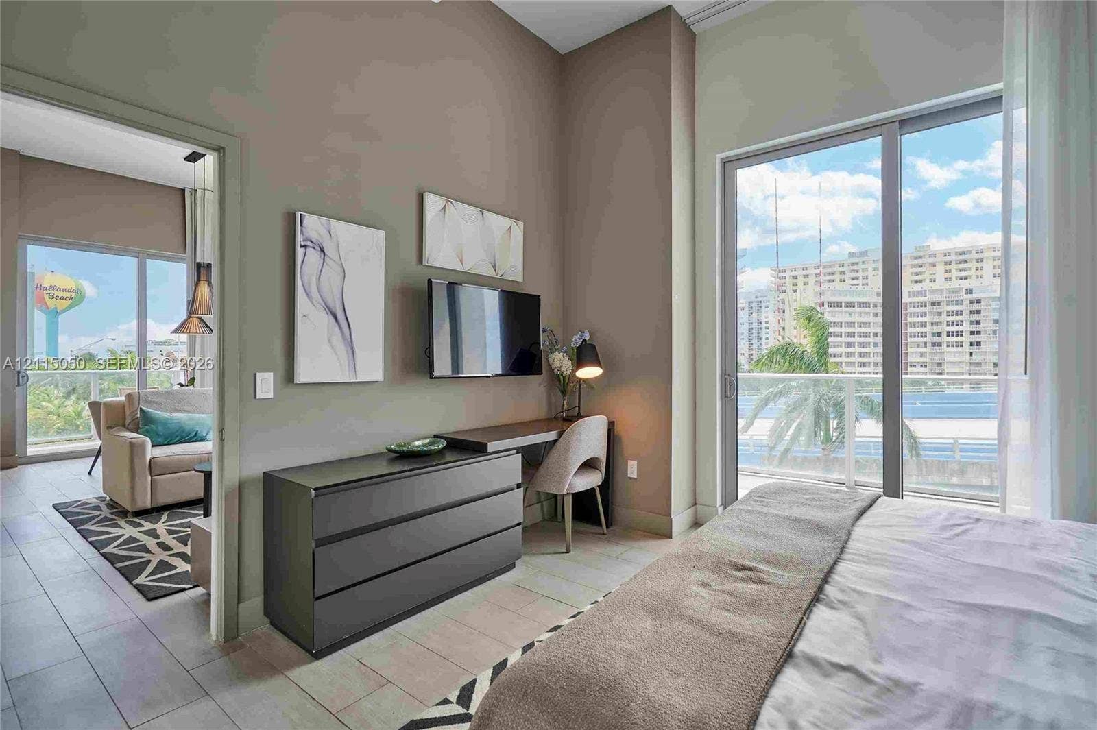 Floor-to-ceiling sliding glass doors, neutral ceramic tile flooring, and a private balcony with glass railing