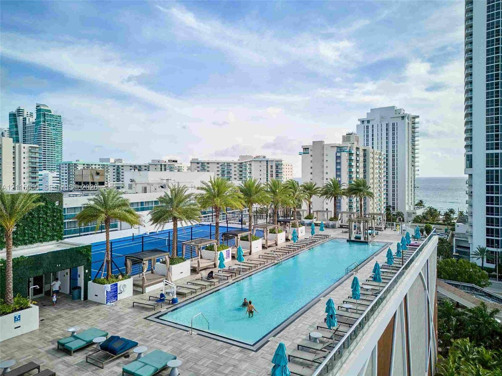 Rooftop terrace featuring a lap pool, a hard-court surface, integrated palm tree landscaping, and a vertical greenery wall