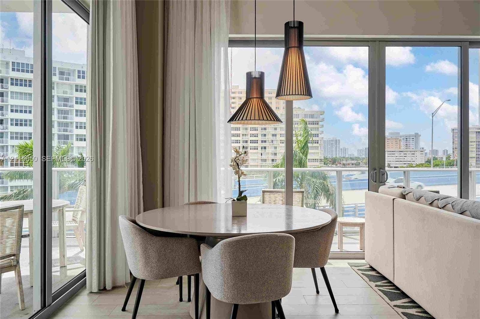 Floor-to-ceiling glass panel doors, dual tapered pendant lighting fixtures, and light-toned flooring
