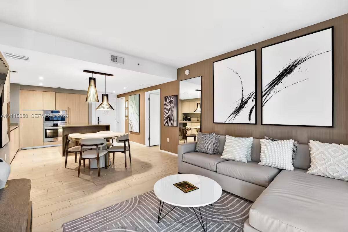 Living area featuring light wood-finish flooring, vertical slat accent wall, and built-in stainless steel wall oven