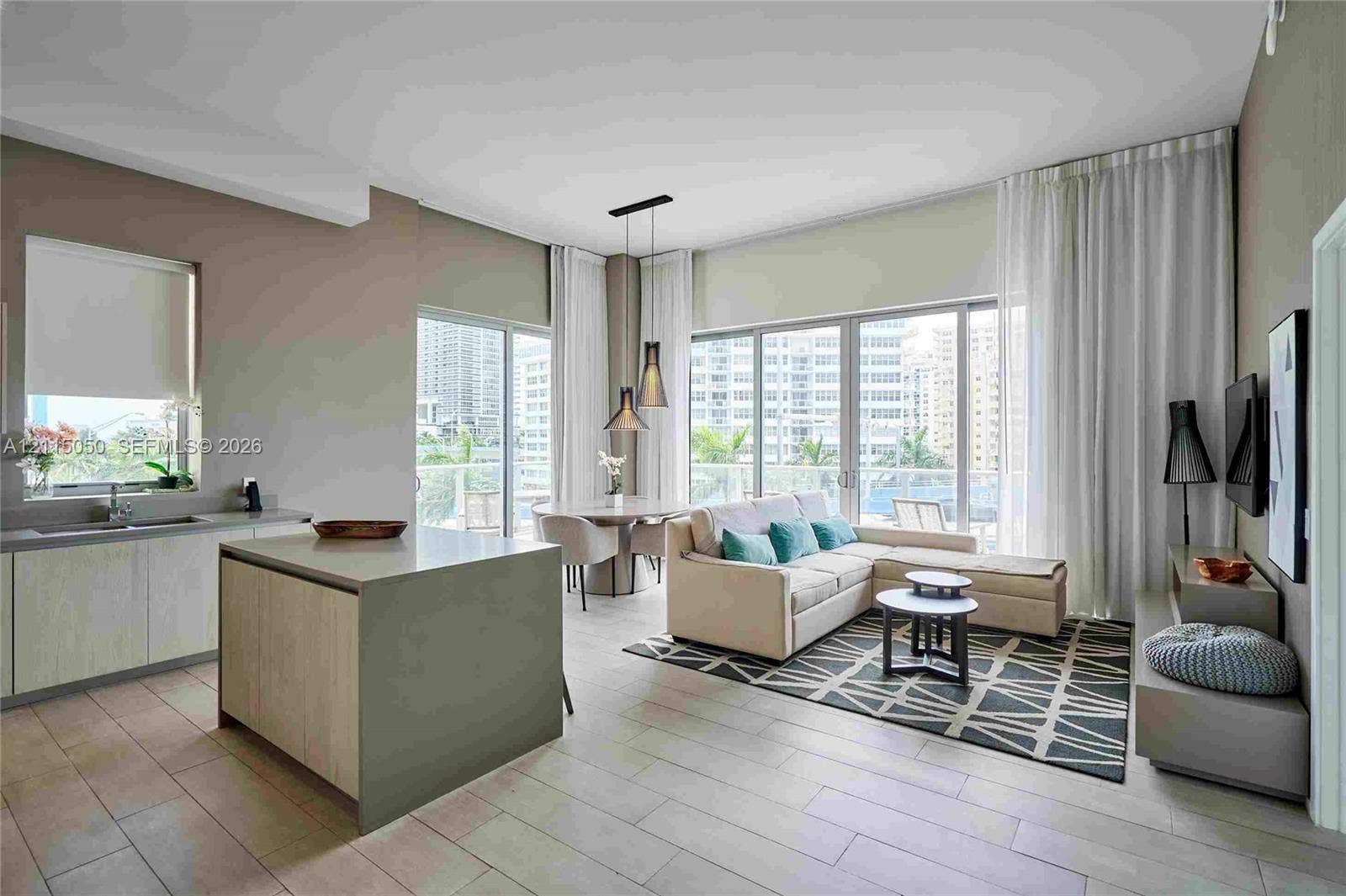 Open-concept interior featuring floor-to-ceiling glass panel doors, tile flooring, a central kitchen island with a neutral finish, and dual pendant light fixtures