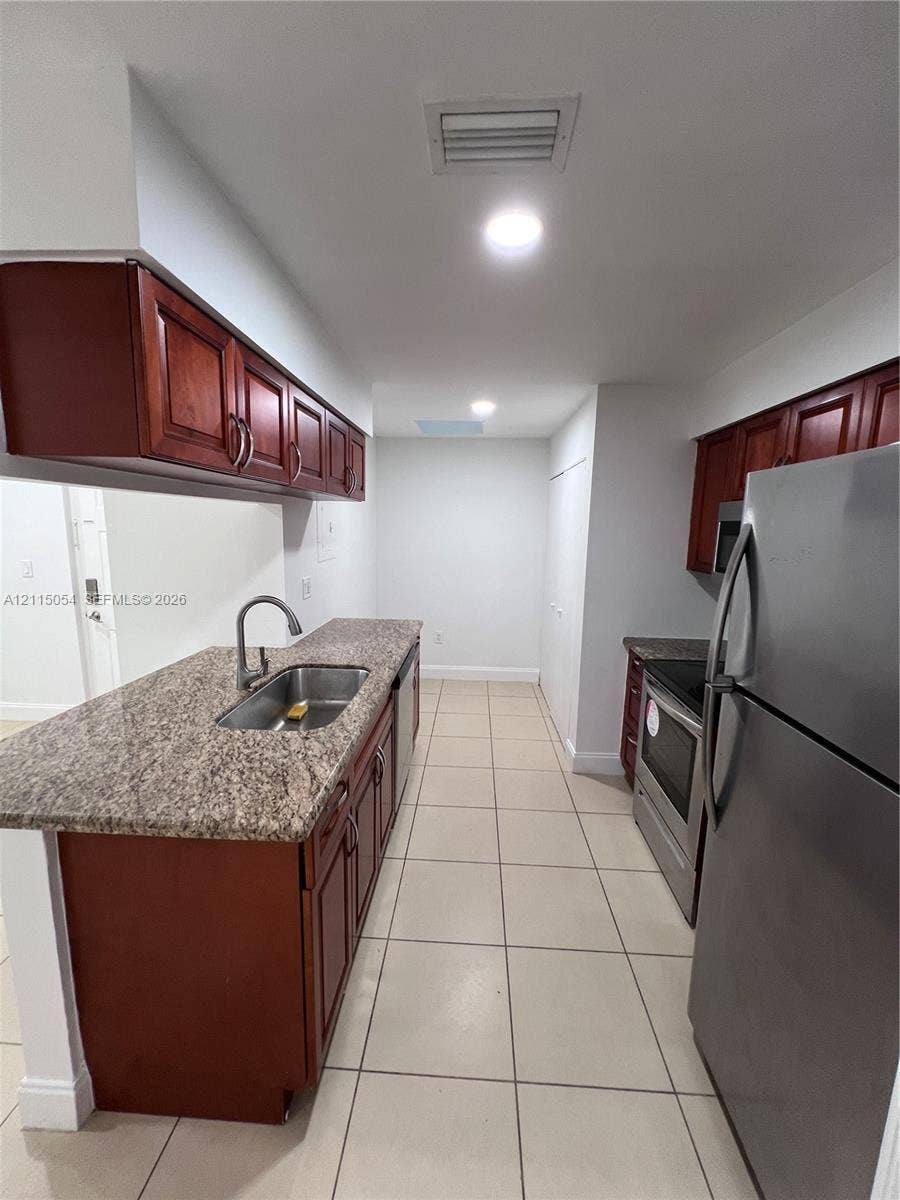 17500 NW 67th Court, #H-19, Hialeah, Hialeah, FL 33015 Kitchen featuring cherry-finish cabinetry, stone-composite countertops, stainless steel appliances, a recessed stainless steel sink, and ceramic tile flooring