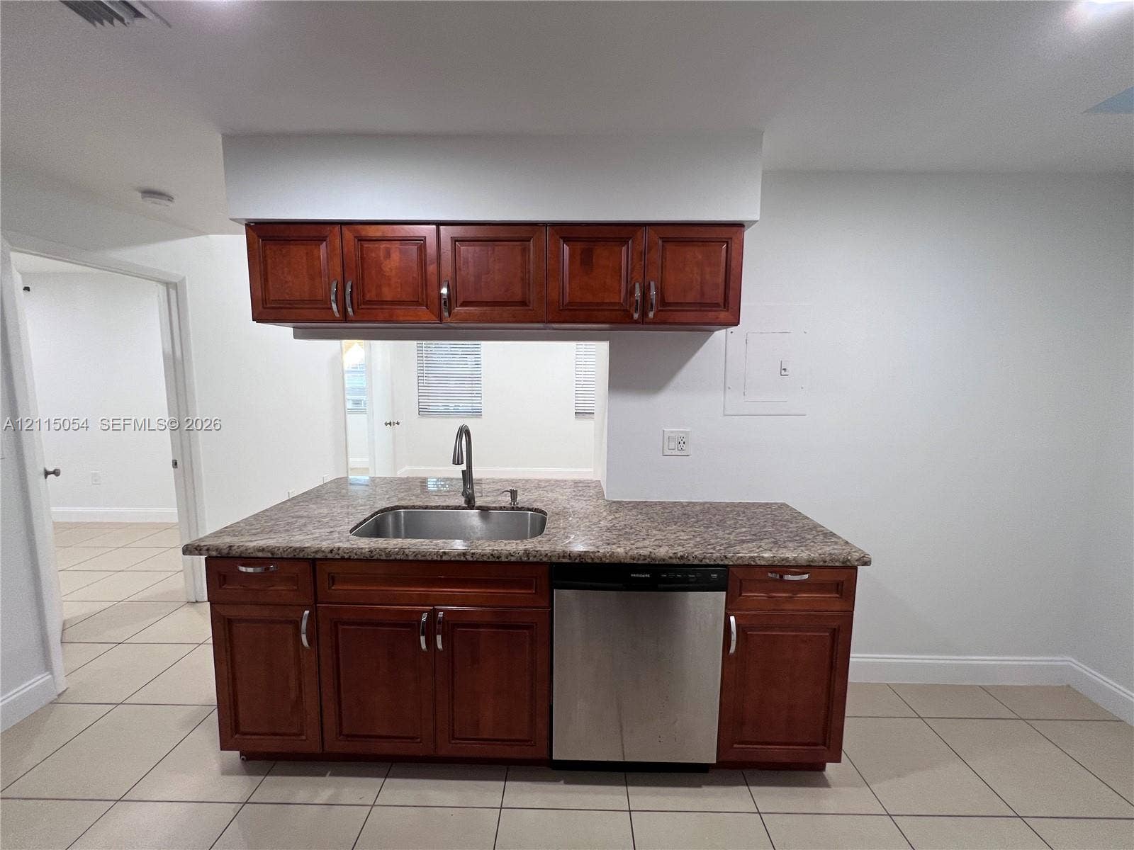 17500 NW 67th Court, #H-19, Hialeah, Hialeah, FL 33015 Kitchen cabinetry featuring rich wood-toned finish, stone-composite countertop, stainless steel undermount sink with arched faucet, and built-in stainless steel dishwasher