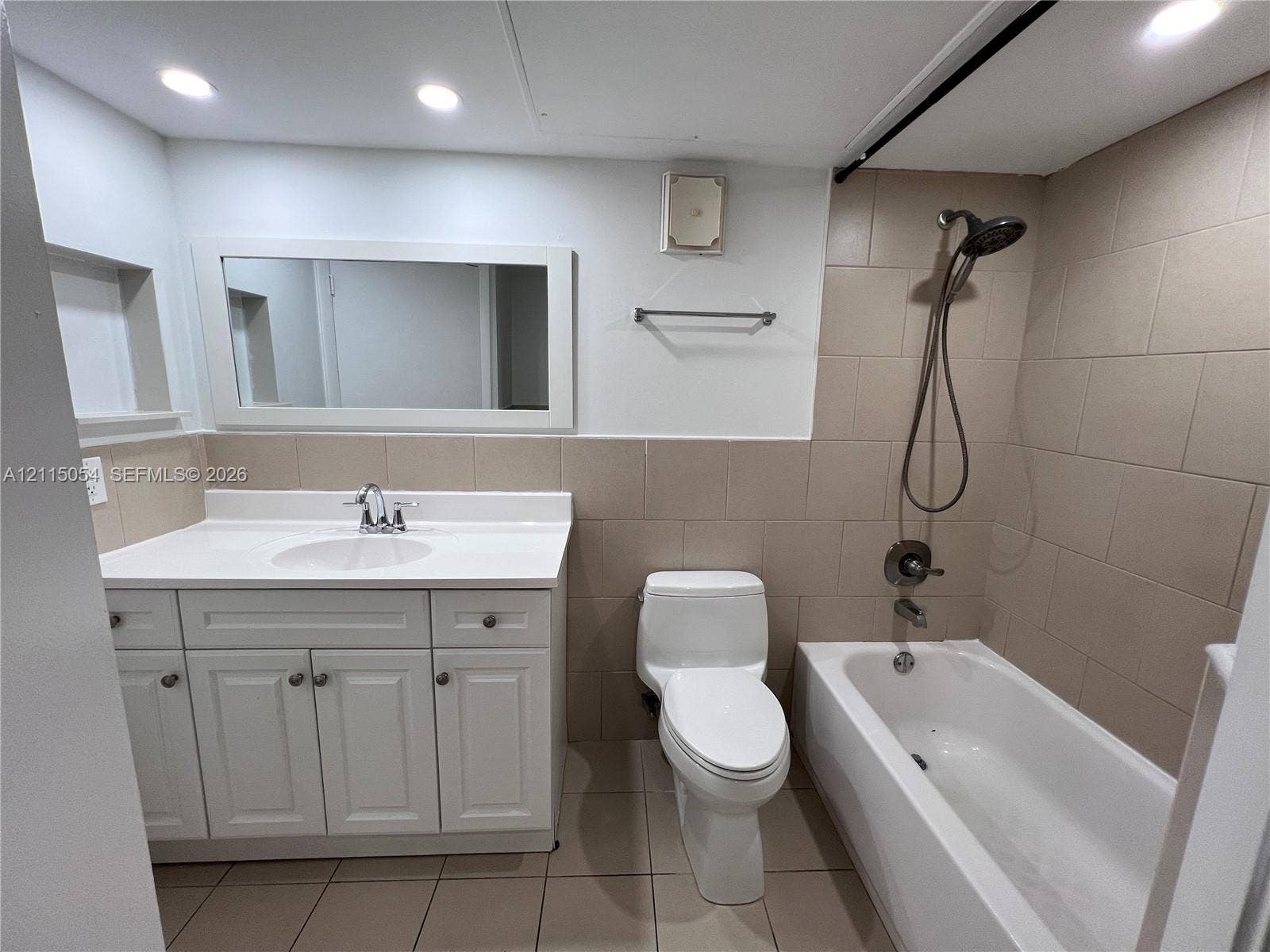 17500 NW 67th Court, #H-19, Hialeah, Hialeah, FL 33015 Bathroom featuring a white vanity cabinet with an integrated countertop sink, wall-mounted rectangular mirror, recessed lighting, and a neutral tile surround in the shower area