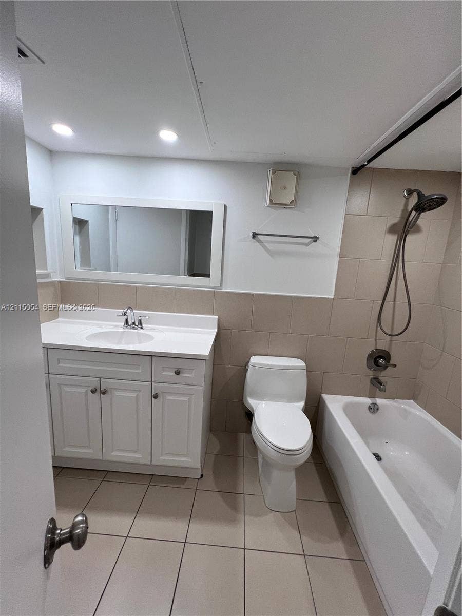 17500 NW 67th Court, #H-19, Hialeah, Hialeah, FL 33015 Bathroom featuring a white vanity cabinet with an integrated sink and countertop, large rectangular mirror, tile flooring, and a bathtub with a wall-mounted shower head and tile surround