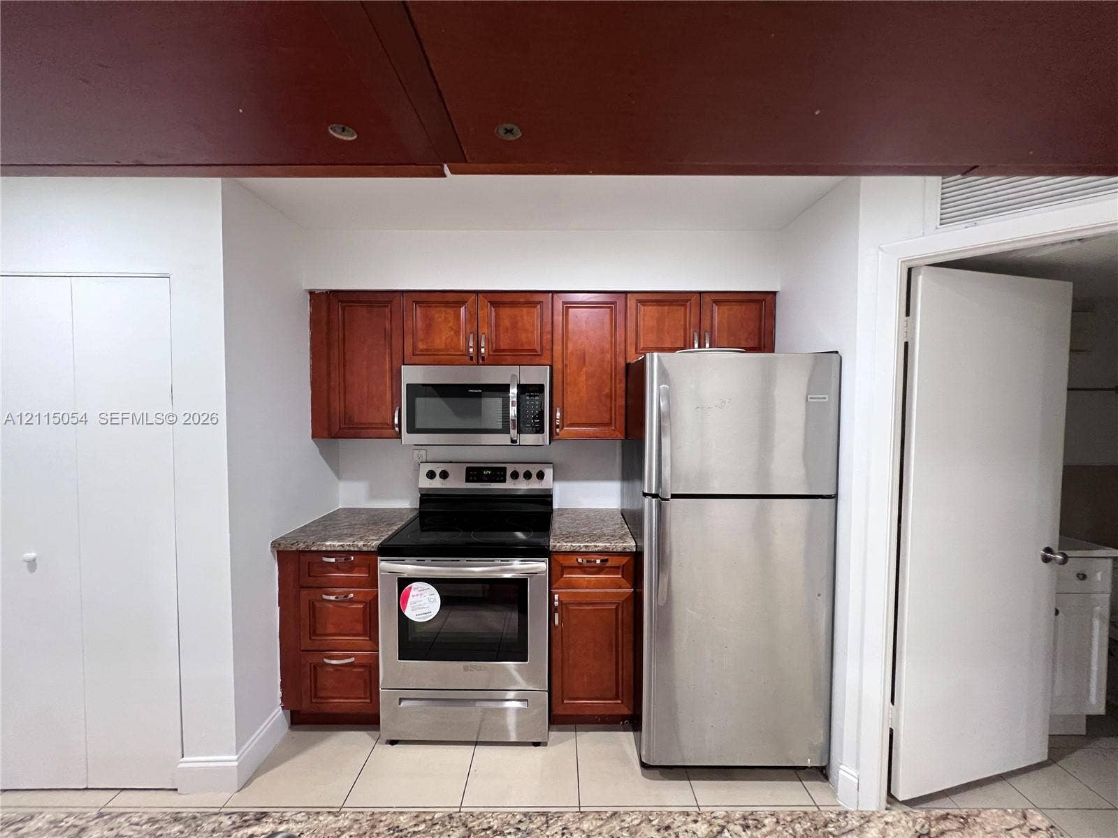 17500 NW 67th Court, #H-19, Hialeah, Hialeah, FL 33015 Kitchen featuring wood-finish cabinetry, stone-patterned countertops, stainless steel appliances, and tile flooring