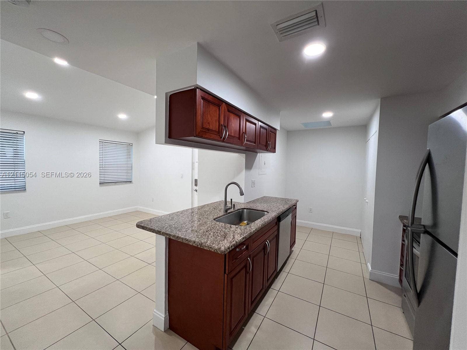 17500 NW 67th Court, #H-19, Hialeah, Hialeah, FL 33015 Kitchen featuring an island with a stone-finish countertop, stainless steel undermount sink, recessed lighting, tile flooring, and wood-finish cabinetry