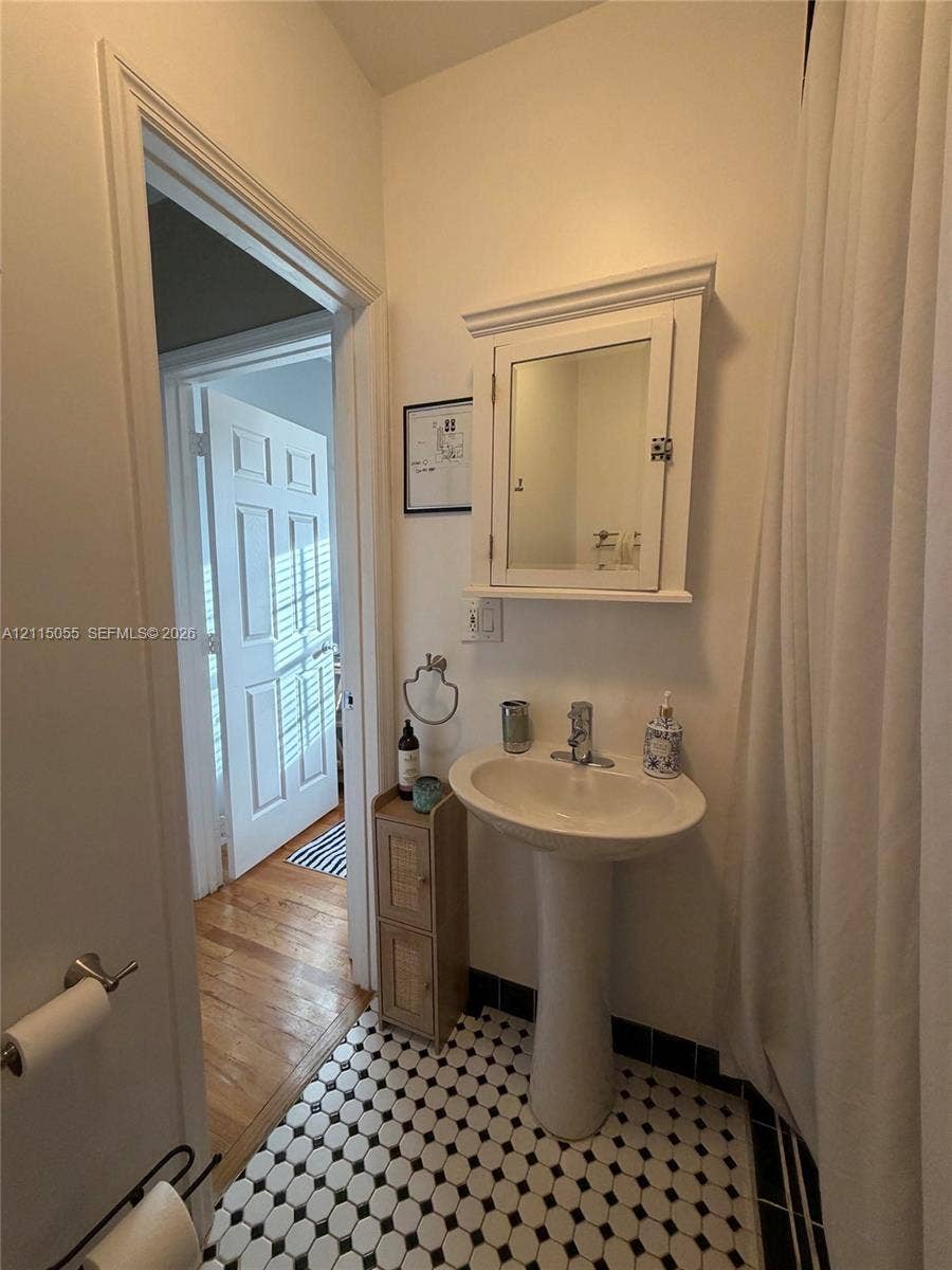 11728 NE 6th Avenue, #2, Biscayne Park, Biscayne Park, FL 33161 Pedestal sink with polished chrome faucet, wall-mounted medicine cabinet with mirror, and black-and-white penny tile flooring