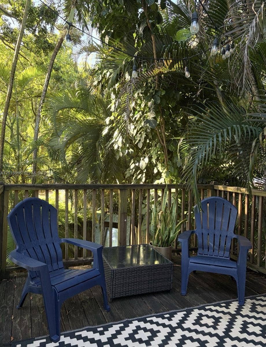 11728 NE 6th Avenue, #2, Biscayne Park, Biscayne Park, FL 33161 Outdoor wood deck featuring vertical wood railing, overhead string lighting, and mature perimeter trees