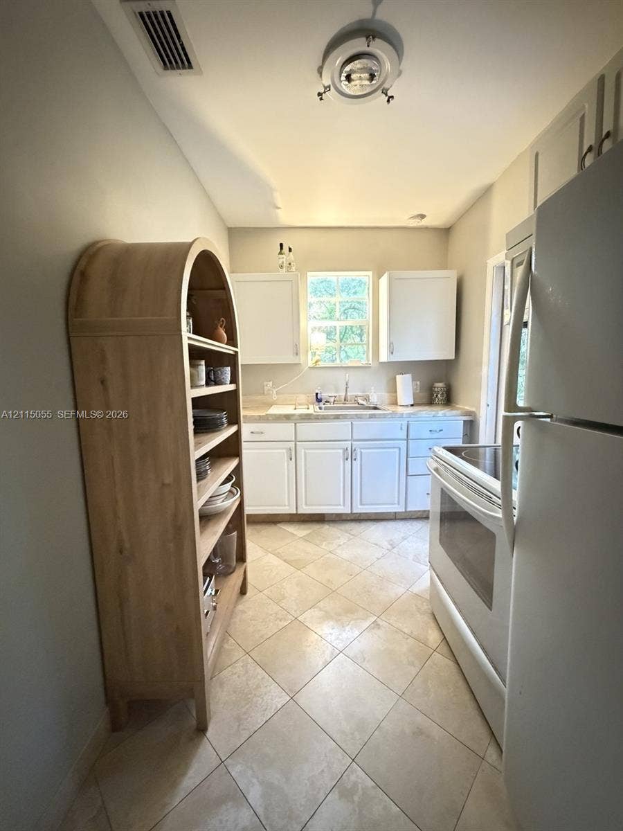 11728 NE 6th Avenue, #2, Biscayne Park, Biscayne Park, FL 33161 Kitchen featuring white shaker-style cabinetry, neutral-toned countertops, tile flooring laid on a diagonal, and stainless steel sink basin