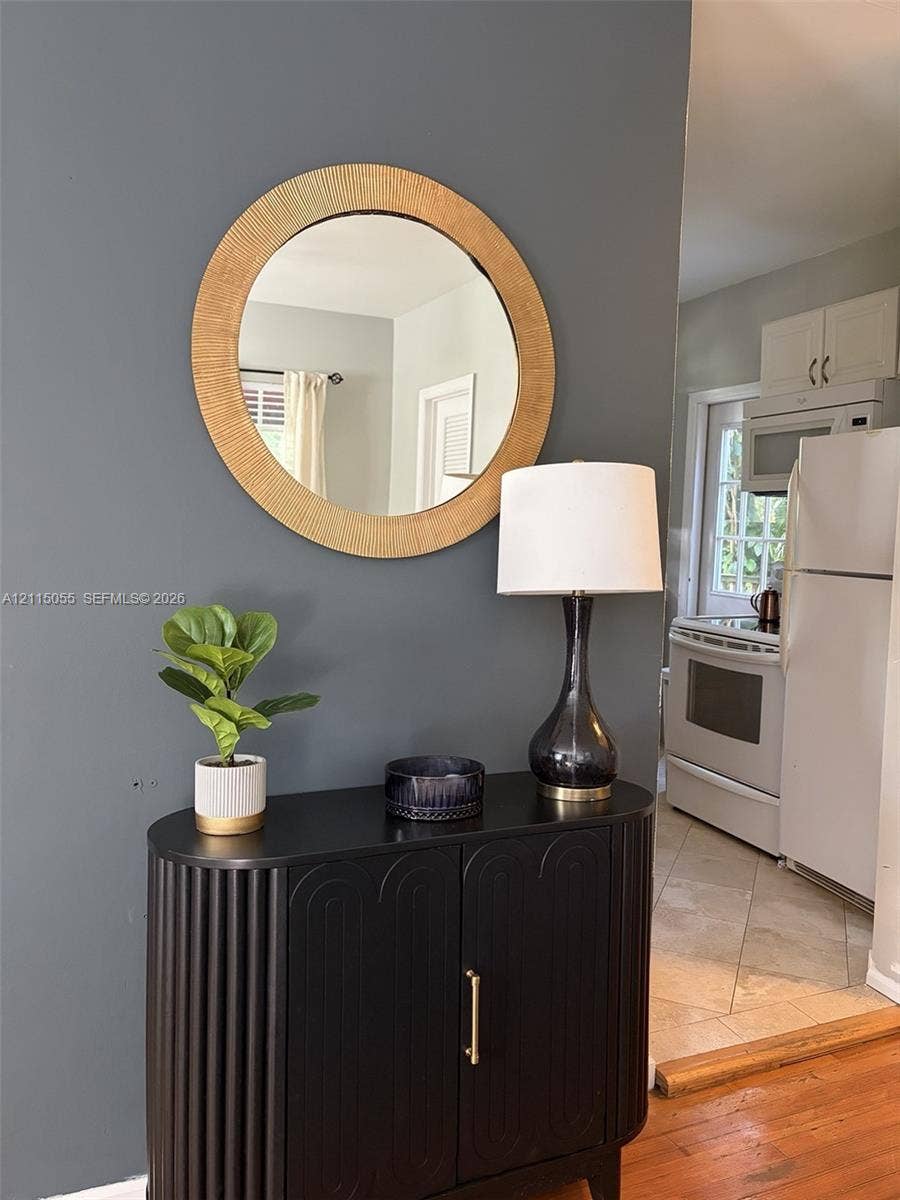 11728 NE 6th Avenue, #2, Biscayne Park, Biscayne Park, FL 33161 Charcoal-toned accent wall featuring a circular textured mirror and hardwood flooring
