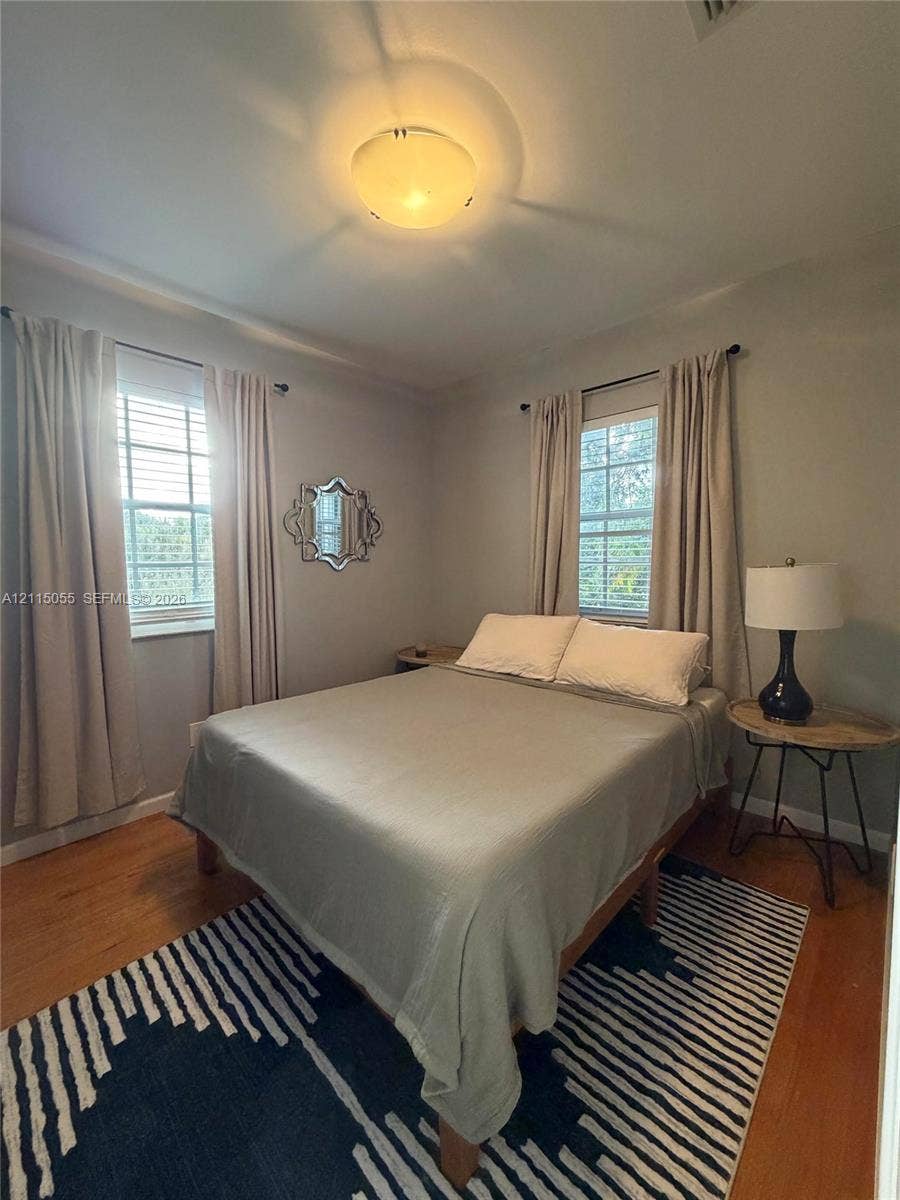 11728 NE 6th Avenue, #2, Biscayne Park, Biscayne Park, FL 33161 Bedroom featuring wood-finish flooring, two windows with double-hung frames, and a flush-mount ceiling light fixture