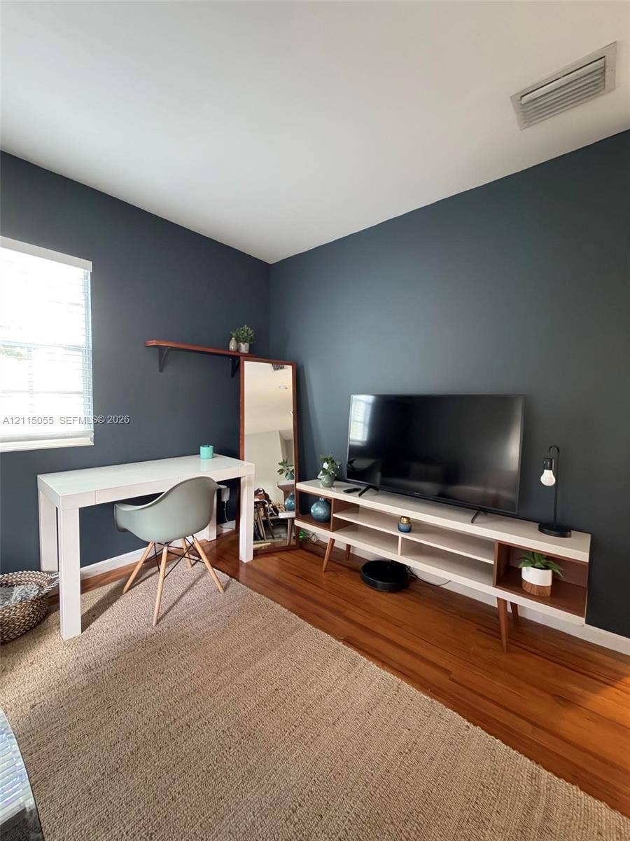 11728 NE 6th Avenue, #2, Biscayne Park, Biscayne Park, FL 33161 Room featuring dark accent wall, wood-finish flooring, and window with white horizontal blinds