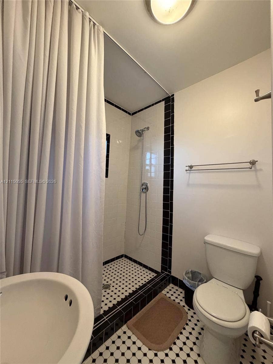 11728 NE 6th Avenue, #2, Biscayne Park, Biscayne Park, FL 33161 Full bathroom featuring a shower stall with white wall tile, a hand-held shower fixture, and a black-and-white patterned tile floor