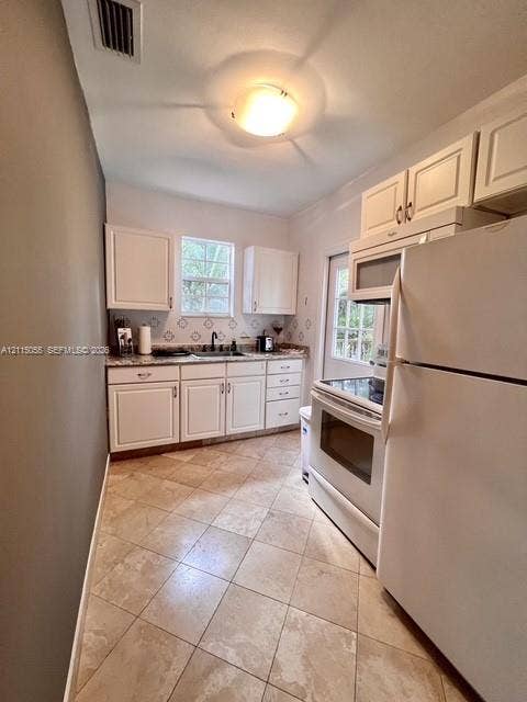 11728 NE 6th Avenue, #2, Biscayne Park, Biscayne Park, FL 33161 Kitchen featuring white cabinetry, patterned backsplash tile, stone-finish countertops, diagonal tile flooring, and integrated white appliances