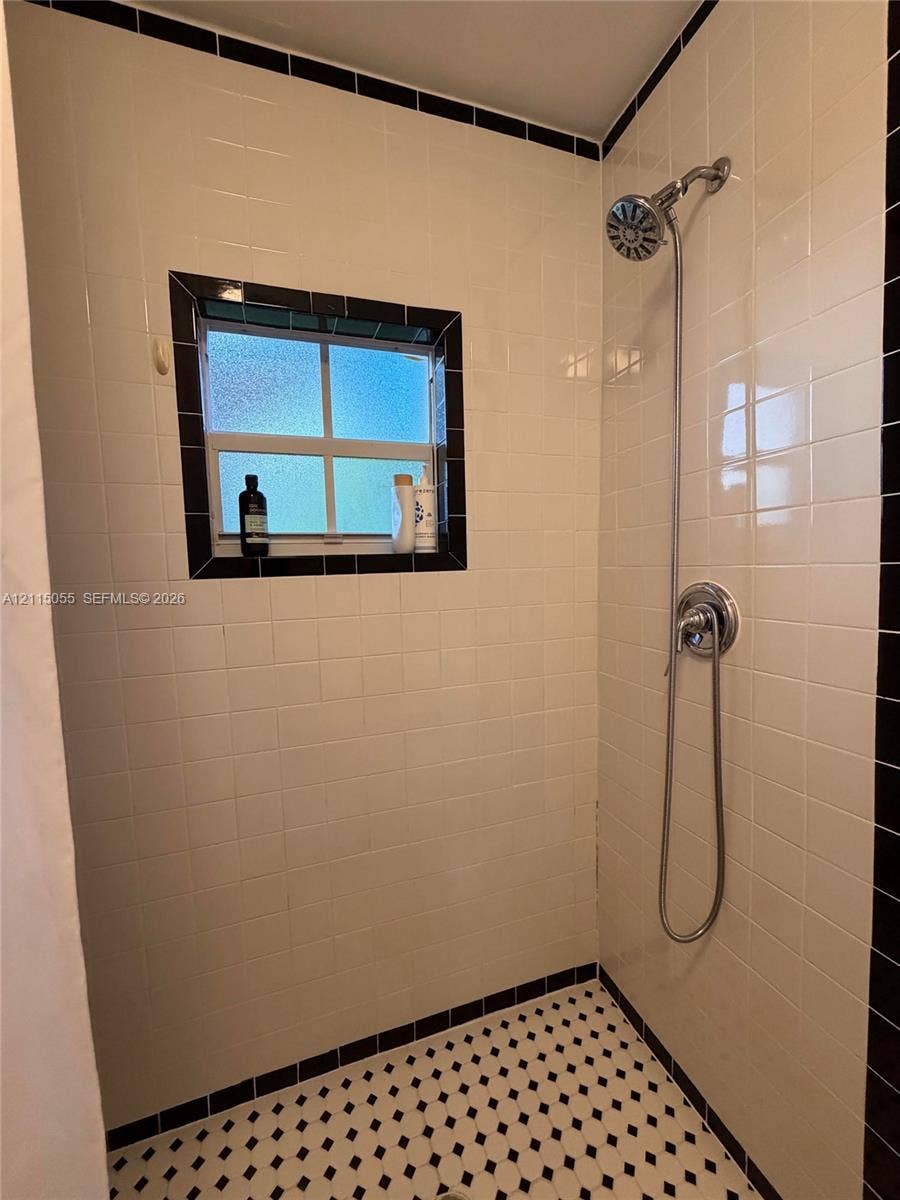 11728 NE 6th Avenue, #2, Biscayne Park, Biscayne Park, FL 33161 Walk-in shower featuring white subway wall tile with black accent trim, a handheld showerhead, a recessed window, and geometric patterned floor tile