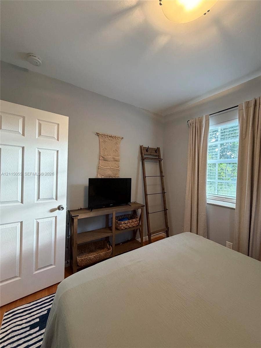 11728 NE 6th Avenue, #2, Biscayne Park, Biscayne Park, FL 33161 Neutral-toned interior featuring wood-finish flooring, a six-panel interior door, and a single-hung window with interior blinds