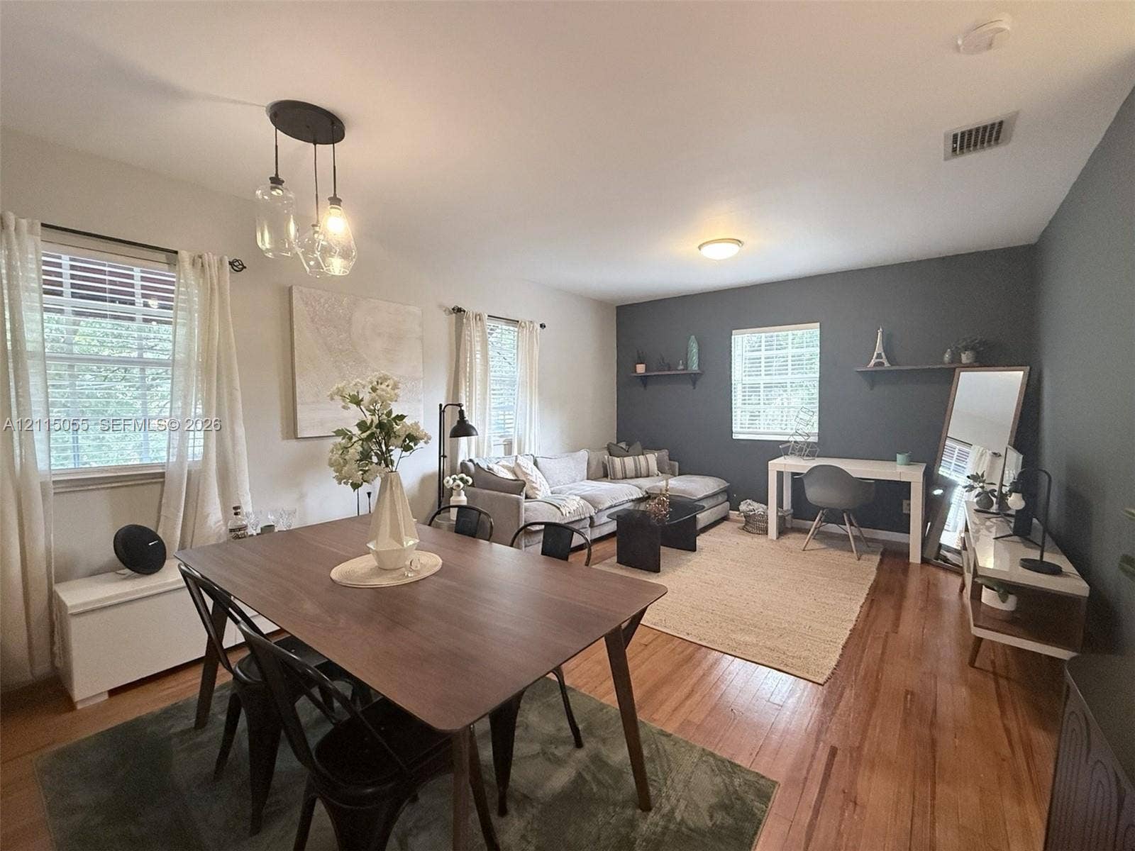 11728 NE 6th Avenue, #2, Biscayne Park, Biscayne Park, FL 33161 Living space featuring wood-finish flooring, a multi-light pendant fixture, and a dark-toned accent wall