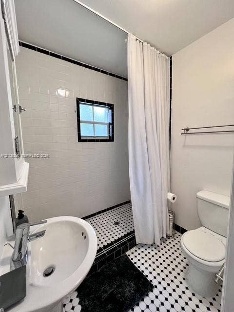 11728 NE 6th Avenue, #2, Biscayne Park, Biscayne Park, FL 33161 Bathroom featuring a pedestal sink with a chrome faucet, black and white hex floor tiling, white subway-style wall tiling with black accent trim, and a built-in recessed shower area with a window