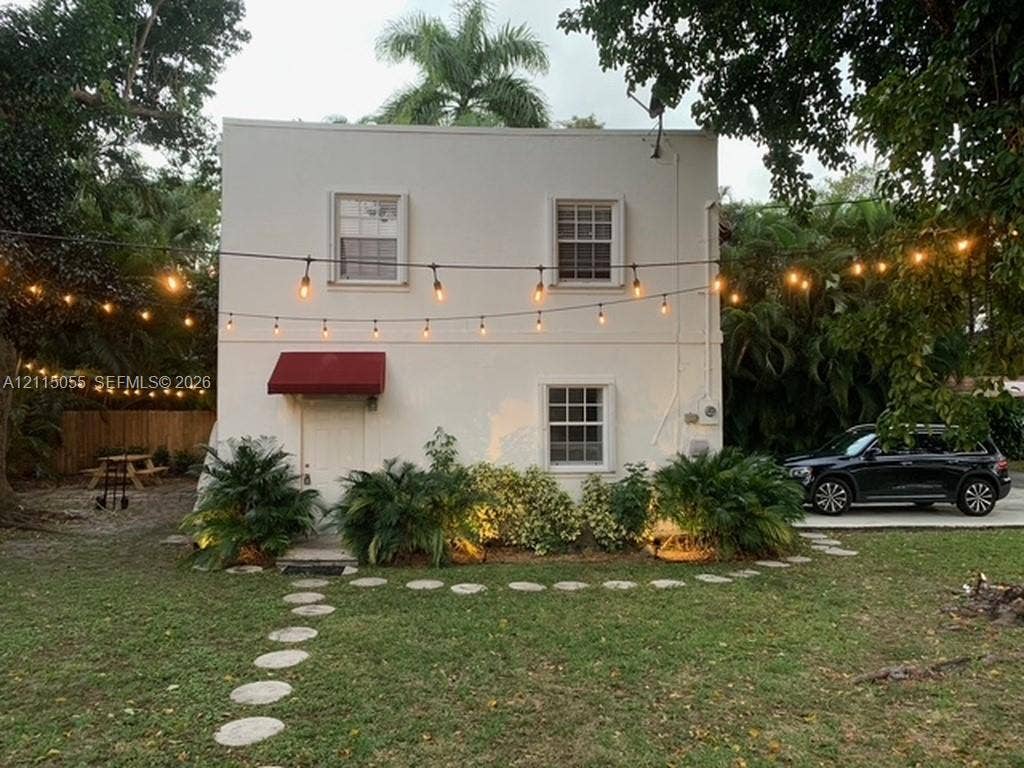 11728 NE 6th Avenue, #2, Biscayne Park, Biscayne Park, FL 33161 Two-story exterior featuring a smooth stucco finish, double-hung multi-pane windows, a red fabric awning, and a stone paver walkway