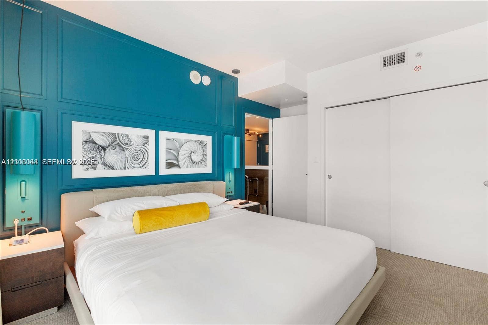 17315 Collins Avenue, #1808, Sunny Isles Beach, FL 33160 Paneled accent wall with integrated light fixtures, custom bedside cabinetry, and sliding closet doors