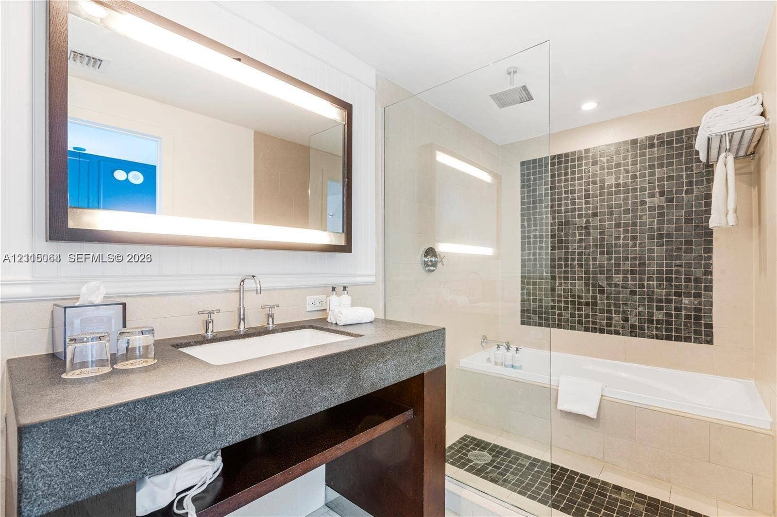 17315 Collins Avenue, #1808, Sunny Isles Beach, FL 33160 Bathroom featuring a floating dark wood vanity with a stone countertop, an integrated rectangular sink, a frameless glass-enclosed shower, and a built-in soaking tub with decorative tile inlay