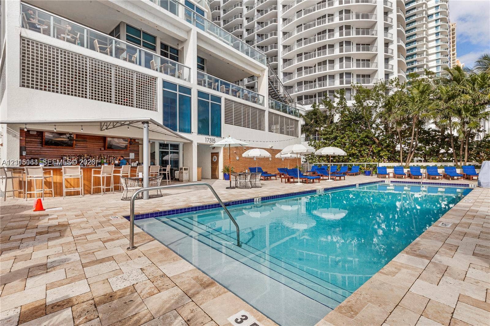 17315 Collins Avenue, #1808, Sunny Isles Beach, FL 33160 Swimming pool with tiled decking, built-in bar with wood-paneled walls, and structural balconies