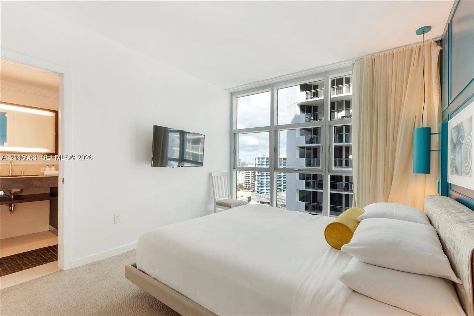 17315 Collins Avenue, #1808, Sunny Isles Beach, FL 33160 Floor-to-ceiling windows with grid-pattern frames, custom blue-toned paneling, modern wall-mounted cylinder lighting, and neutral carpeting
