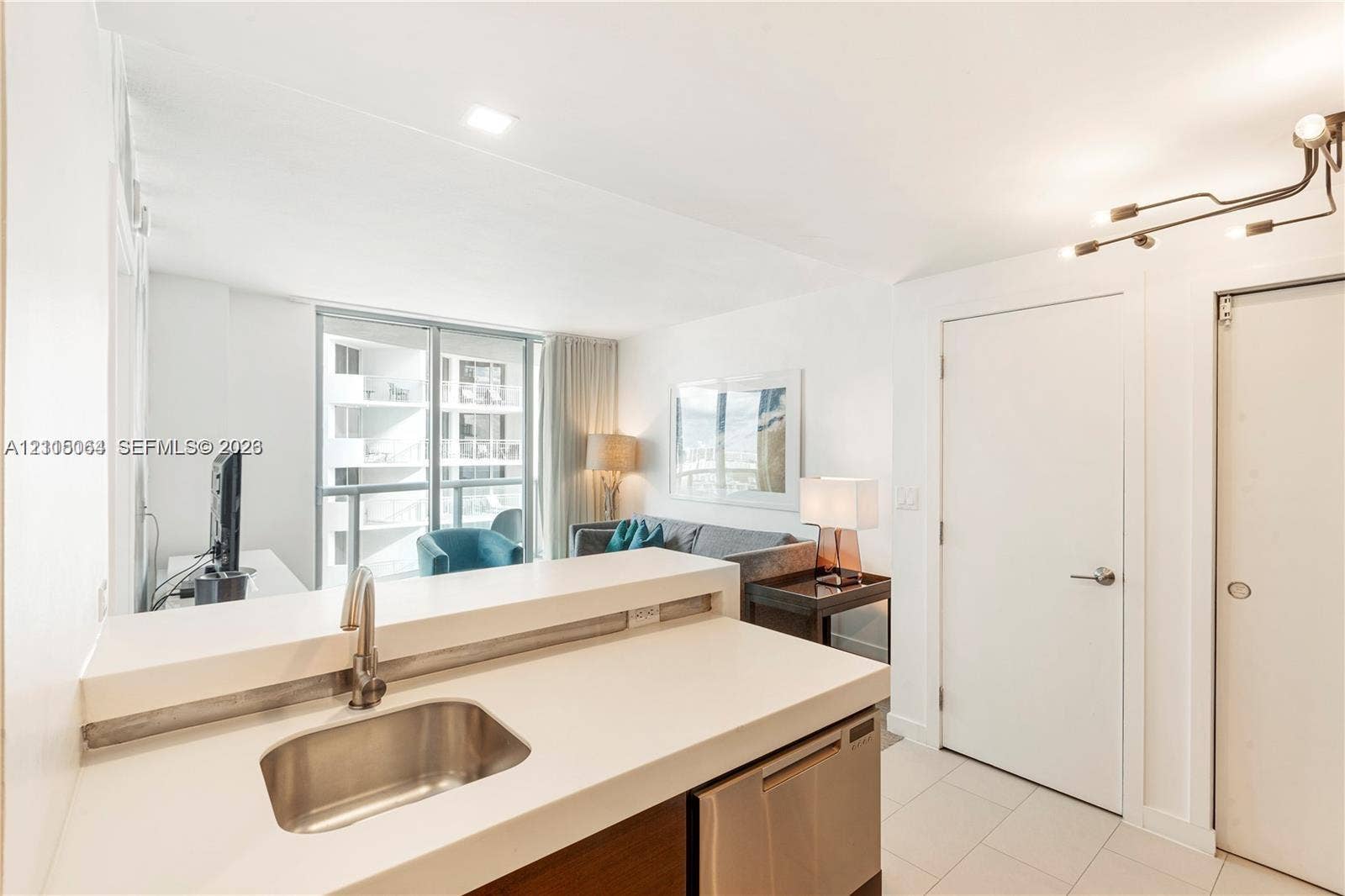 17315 Collins Avenue, #1808, Sunny Isles Beach, FL 33160 Kitchen featuring a white solid-surface countertop, stainless steel undermount sink with a gooseneck faucet, stainless steel dishwasher, modern multi-arm track lighting, and tile flooring