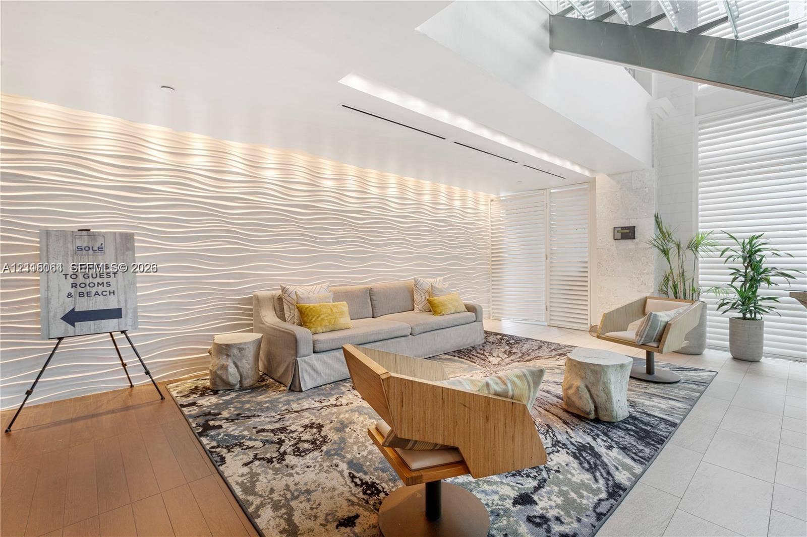 17315 Collins Avenue, #1808, Sunny Isles Beach, FL 33160 Textured, three-dimensional wave-pattern accent wall, high ceilings with integrated recessed lighting, metal-frame open-riser staircase, and floor-to-ceiling slatted window treatments