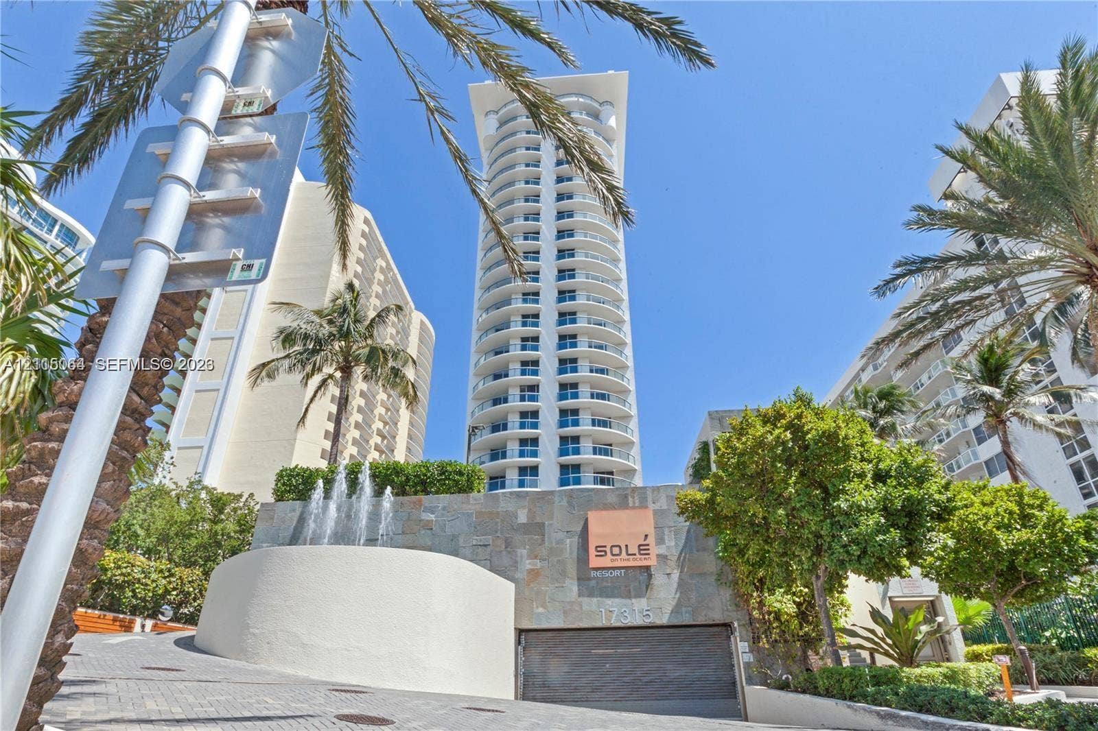 17315 Collins Avenue, #1808, Sunny Isles Beach, FL 33160 High-rise tower featuring rounded balconies, stone-clad entryway, decorative water fountain, and paved driveway