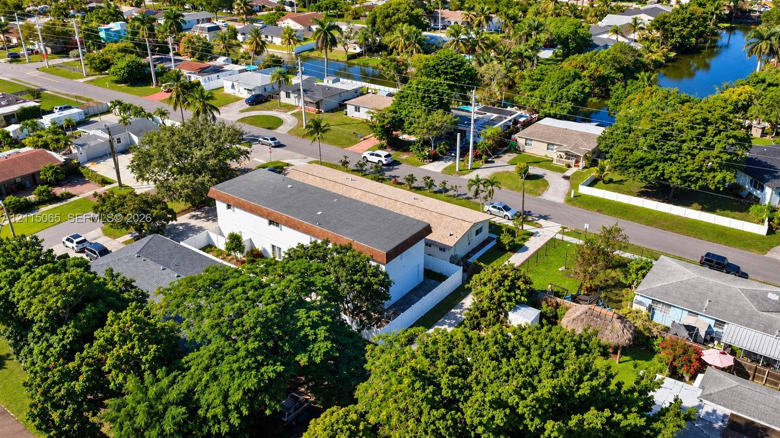 Aerial perspective of a multi-level structure featuring a flat roofline, white exterior siding, and a fenced perimeter