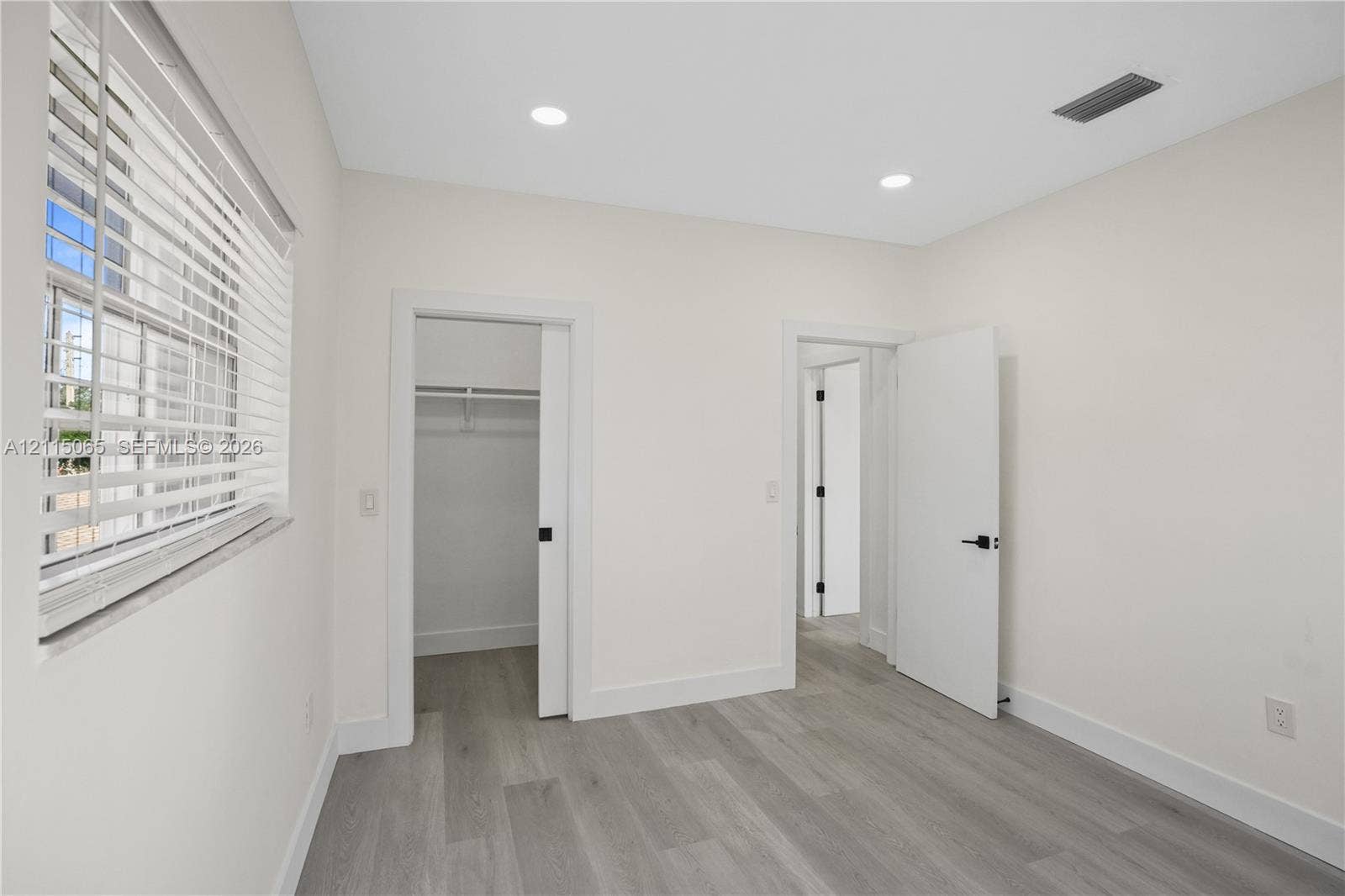 Interior room featuring wood-finish flooring, recessed lighting, a sliding closet door, and window blinds